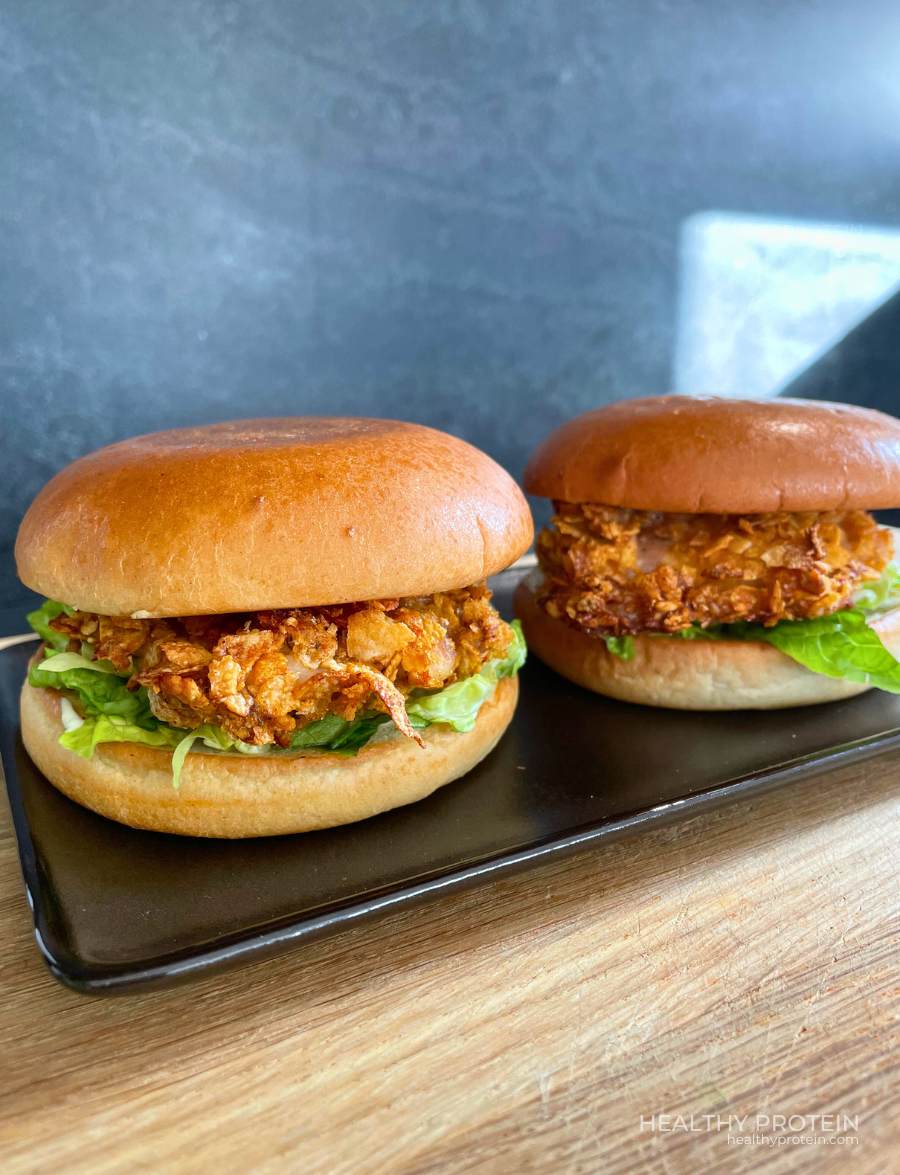 Crispy Fried Chicken Burger on a dark plate served to eat with crispy oven-baked chicken, brioche bun, spicy pickles, romaine lettuce, and light mayonnaise